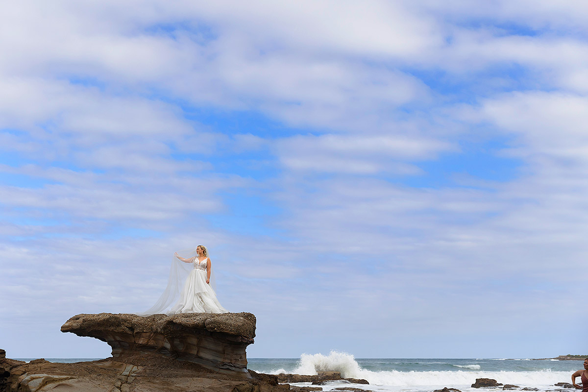 bride on rocks at caves beach wedding